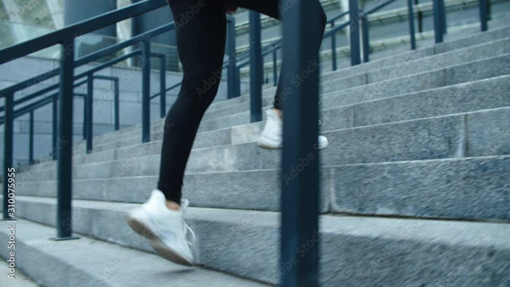 Close up fitness woman climbing up stairs. Woman jogger finishing run exercise