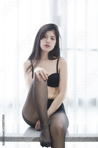 Sexy women wearing black lingerie doing various poses by the window of light