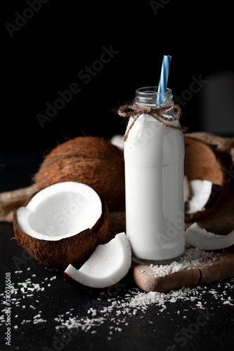 fresh coconut milk in a bottle against a dark background, coconut milkshake on a black table