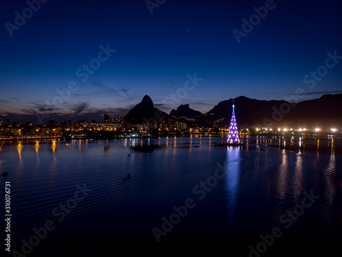 Lights of the floating Christmas tree in the middle of the city lake of Rio de Janeiro during sunset with blue and red colour scheme