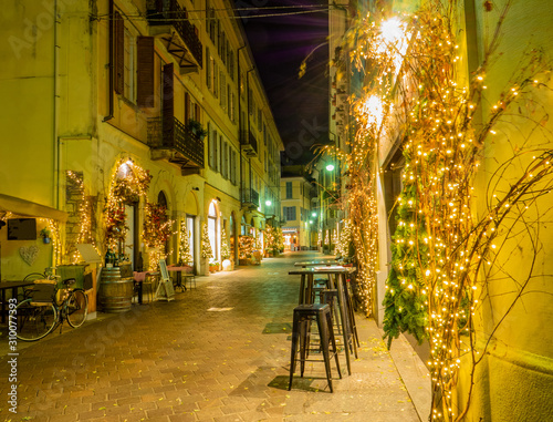 Christmas lights illuminate the deserted streets of the historic center of Como in the night