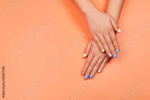 Manicure in trendy colors: coral, rose gold and blue on colorful background. Flat lay style.