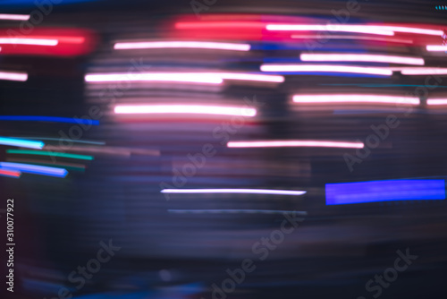 Defocused neon streaks blurred in motion in the dark of the night. Riding or driving a vehicle in the night city. Purple urban abstract.