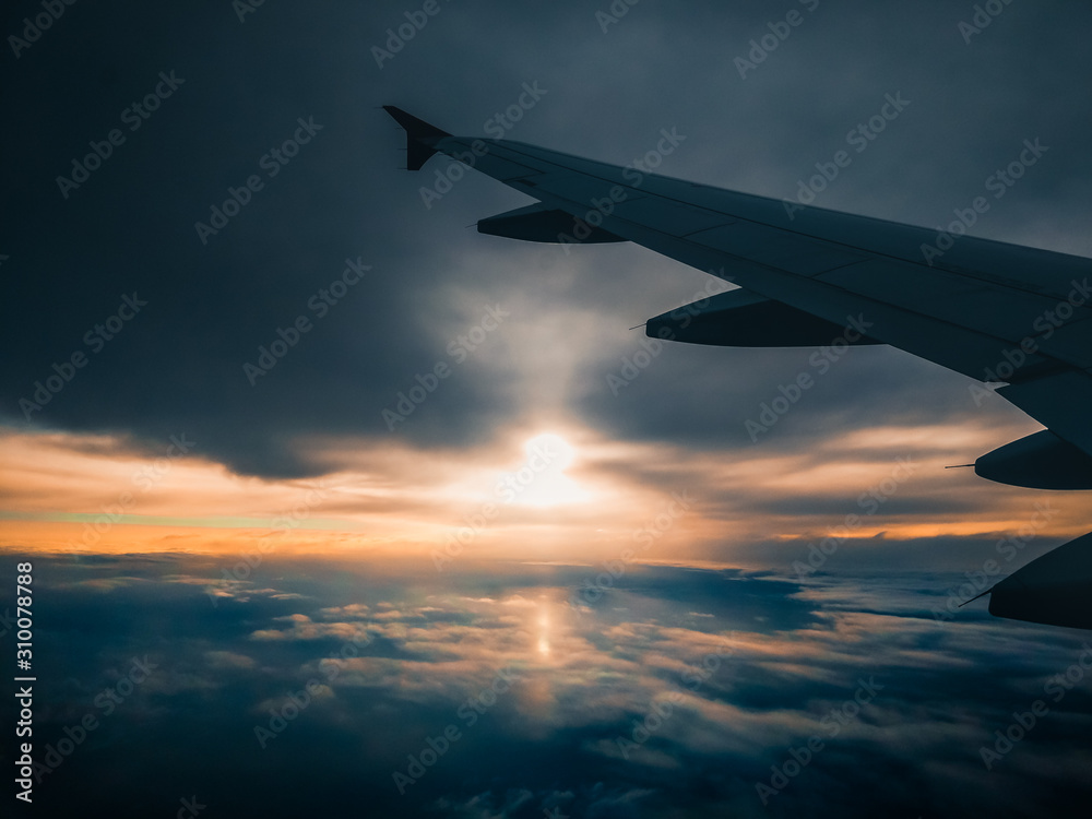 Fototapeta premium Aerial view of dark sunset sky with clouds and airplane wing through an plane window.