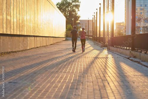 Doing sport together. Back view of a couple in sport clothing running together through the city street. Fitness couple © Svitlana