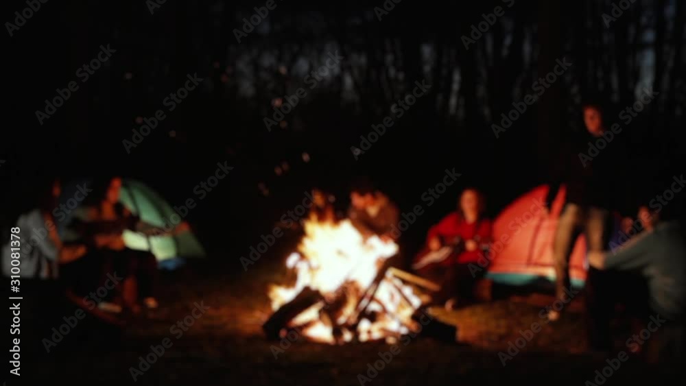 Blurred Background of Camping Tents and Young People around a Campfire in the Forest at Night. Fast Motion.