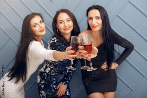 Girls in a studio. Party theme. Ladies in a elegant dress with champagne;