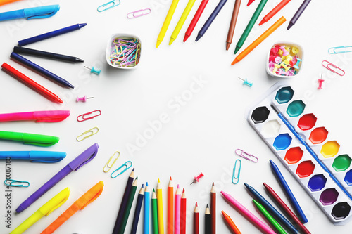 Colorful art supplies arranged in a circle on a white background