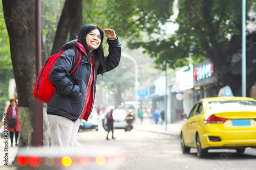 Photography Asian tourist woman standing on pavement and waiting for bus or taxi