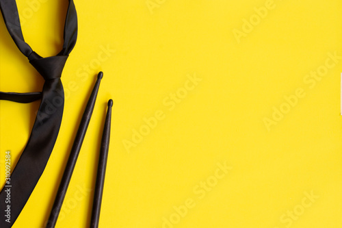 Top view drumsticks and tie over yellow background. Music concept. drummer player, bad men concept.