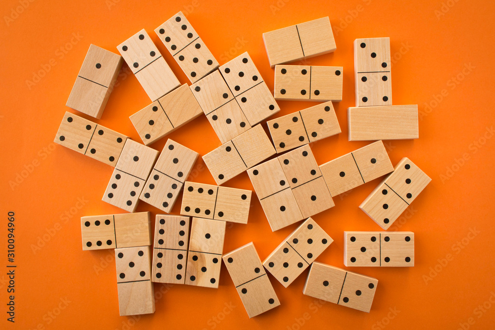 Playing dominoes on a orange table. Leisure games concept. Domino effect.