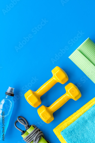 Fototapeta Naklejka Na Ścianę i Meble -  Fitness background - dumbbells, jump rope, sport carpet, water bottle - on blue top-down frame copy space