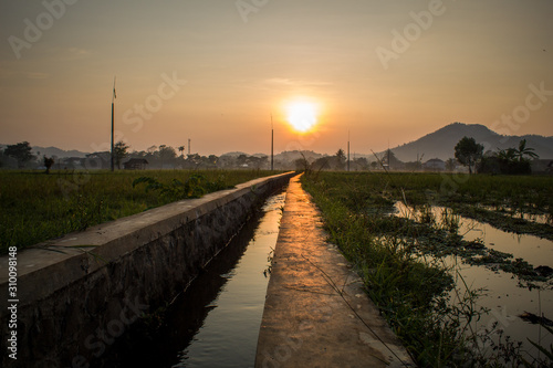Footpath Amidst Canal Against Sky During Sunset © Rizal Kuswandi