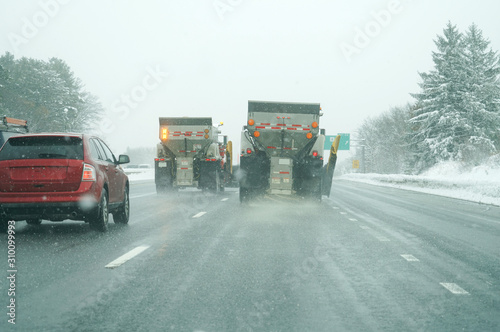 Snowplow spreading salt on the highway photo