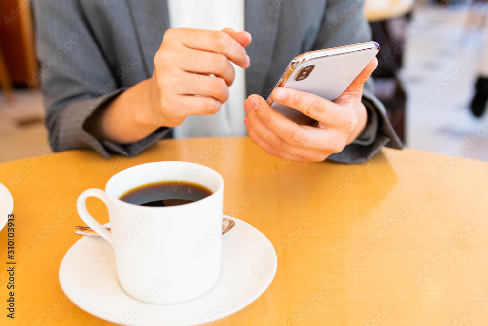 コーヒー片手にスマホを操作する女性 コーヒー片手にスマホを操作する女性