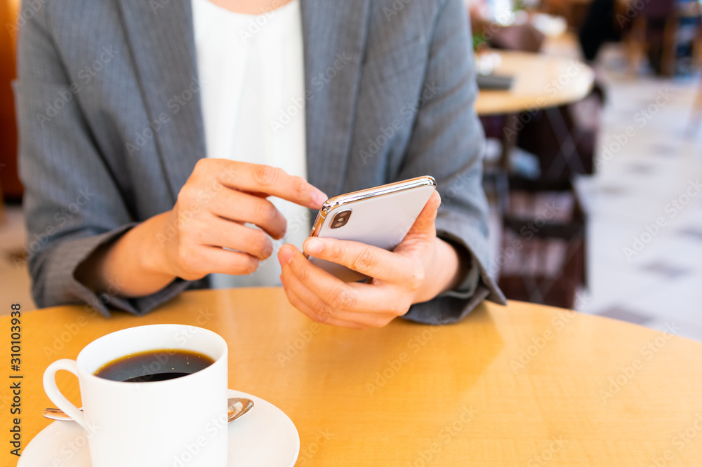 コーヒー片手にスマホを操作する女性 コーヒー片手にスマホを操作する女性