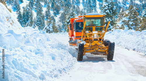The bulldozer cleans snow on the road.