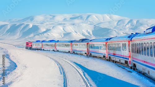 Red diesel train (East express) in motion at the snow covered railway platform - The train connecting Ankara to Kars - Turkey photo