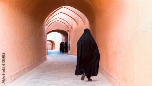 фотографія Muslim woman walking on the narrow street of old adobe Yazd city - IRAN