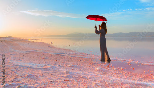 Girl with umbrella in the Maharlu pink lake at sunset - Shiraz, Iran photo