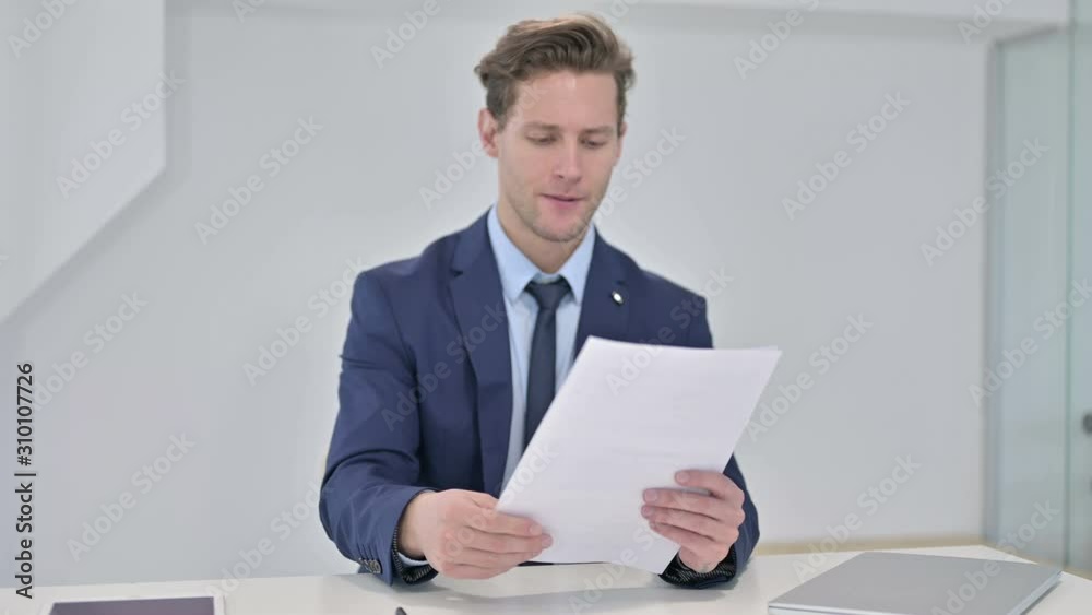 Upset Young Businessman Reading Documents and Reacting to Failure Upset Young Businessman Reading Documents and Reacting to Failure