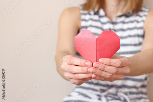 caucasian woman holding paper folded origami heart,  heart health care, insurance, charity donation concept. text area copy space, selective focus