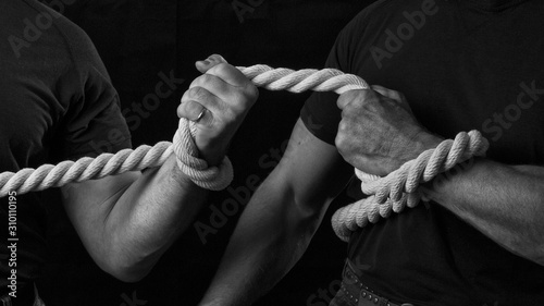 Tug of war. The concept of strength and struggle. Two men are fighting for leadership in tug of war. Men pull a big thick rope.