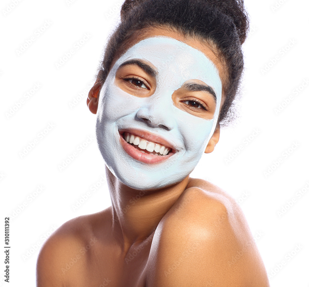 Beautiful African-American woman with facial mask on white background