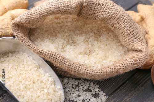 Bag and scoop with raw rice on table