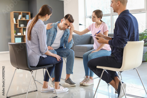 Young people calming sad man during psychological support session