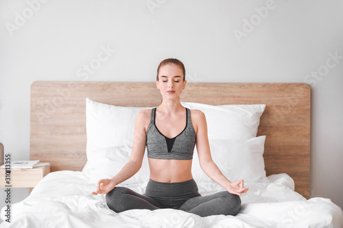 Beautiful young woman practicing yoga in bedroom © Pixel-Shot