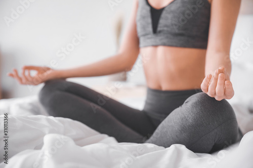 Beautiful young woman practicing yoga in bedroom