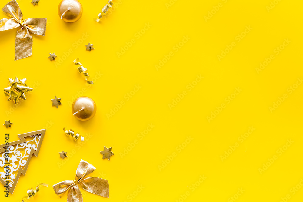 Fototapeta premium New Year card with tree, balls, present box on yellow background top-down frame copy space