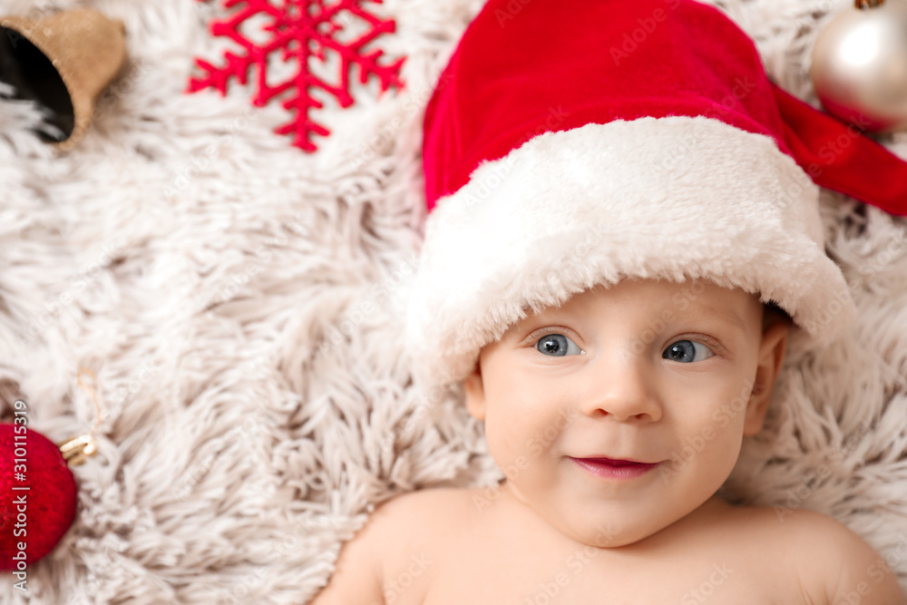 Fototapeta premium Cute little baby in Santa Claus hat lying on plaid