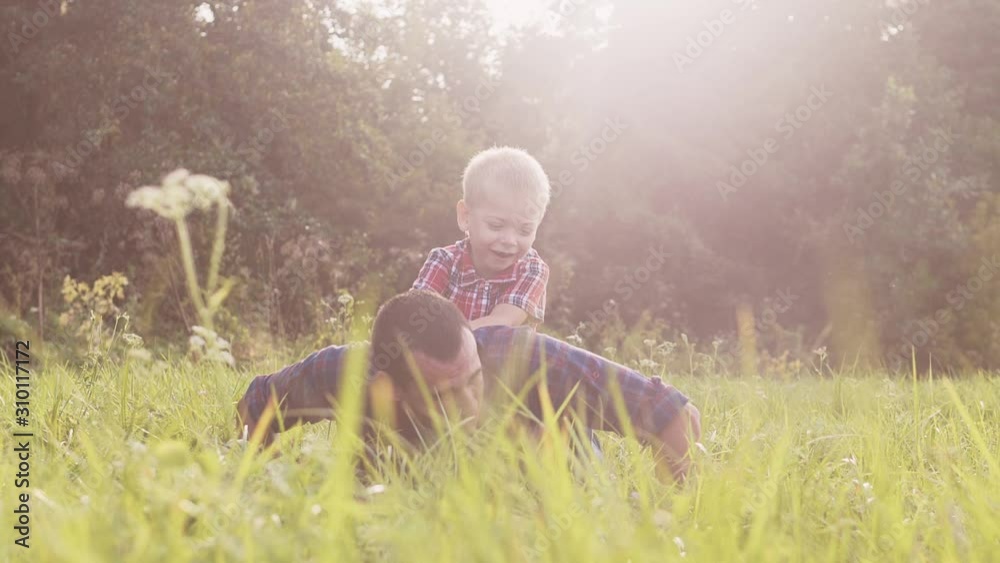 dad and son happy lifestyle family play push ups slow motion funny video . father man and son little a boy push ups in nature laugh and play