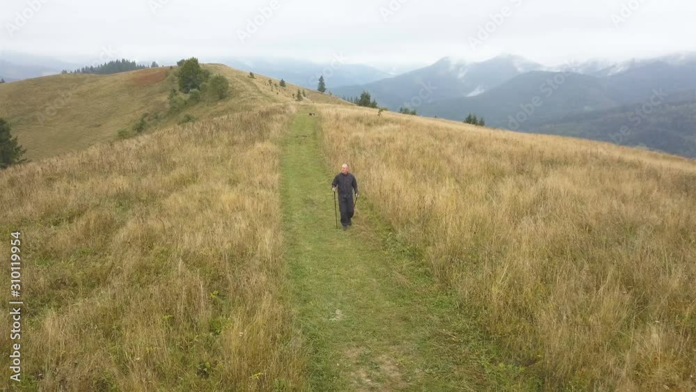 4K Aerial. Man tourist with sticks go on ridge in autumn mountain hill. Front view 4K Aerial. Man tourist with sticks go on ridge in autumn mountain hill. Front view