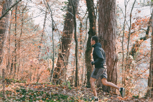 The concept of sport and a healthy lifestyle. A young slender man in sports clothes is engaged in Jogging in the autumn forest or Park. In profile view