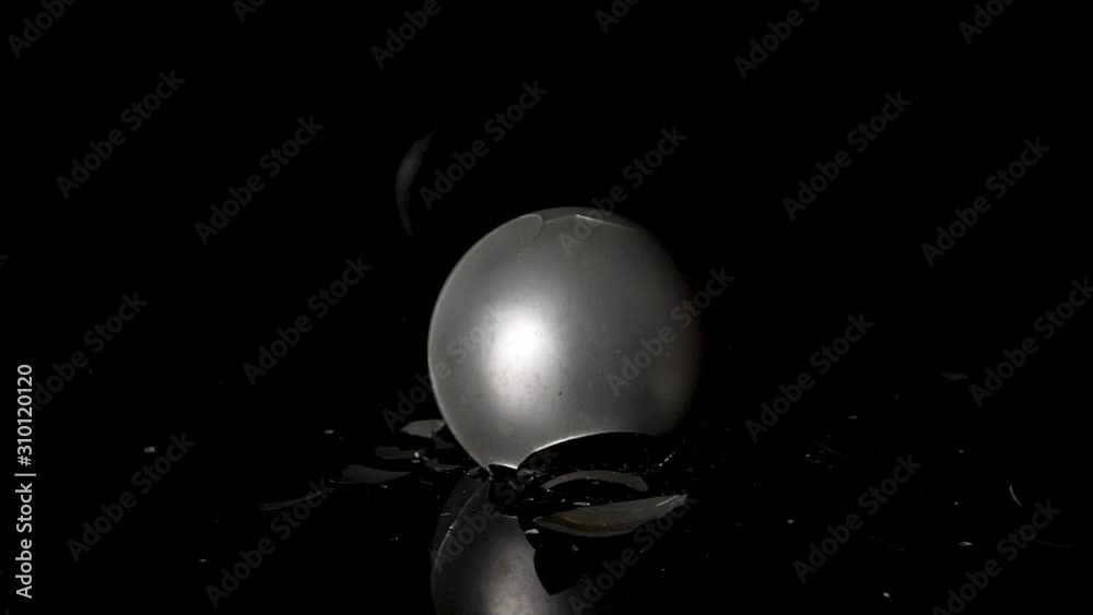 Silver christmas ball drops on black surface and shatters. Static shot. Silver christmas ball drops on black surface and shatters. Static shot.