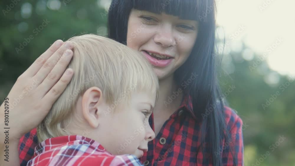 happy family mom and son concept. mom tender childhood video. slow motion video. a mom brunette girl protects caress gently hugs takes care of the son boy blonde outdoors lifestyle happy family mom and son concept. mom tender childhood video. slow motion video. a mom brunette girl protects caress gently hugs takes care of the son boy blonde outdoors lifestyle