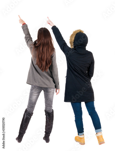 Back view of two pointing young girl in winter jacket.