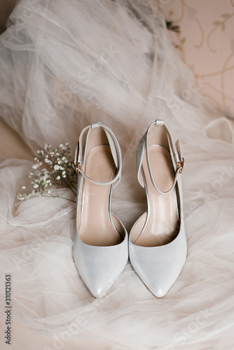 Light gray shoes for the bride and a sprig of gypsophila on a white tulle. Accessories for women