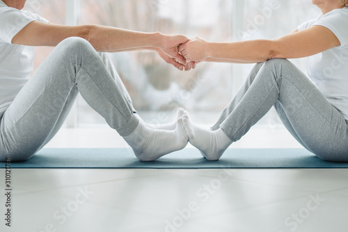 Sports and healthy lifestyle. Cropped image of beautiful middle aged couple doing stretching. Healthy joints and back.
