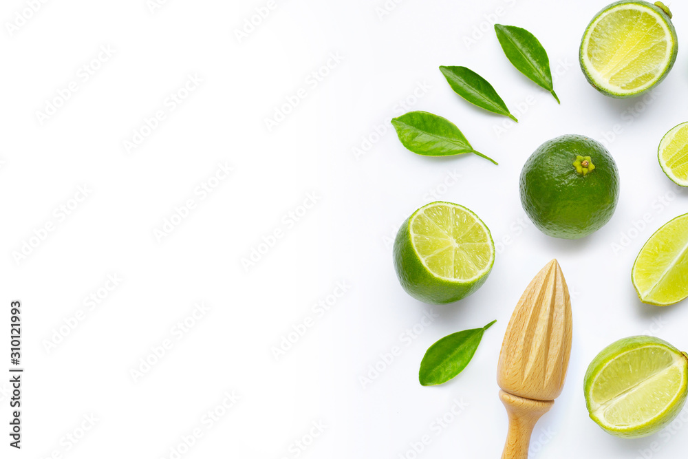 Fresh limes and leaves with wooden juicer on white