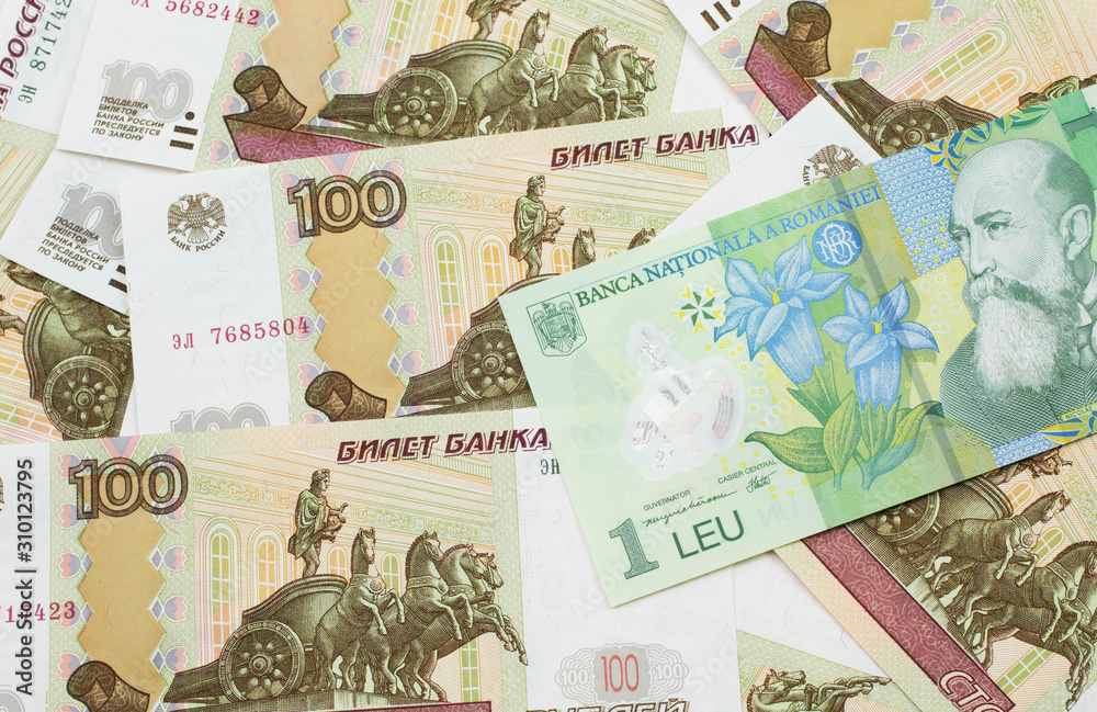 A close up image of a green Romanian one leu bank note on a background of Russian one hundred ruble bank notes
