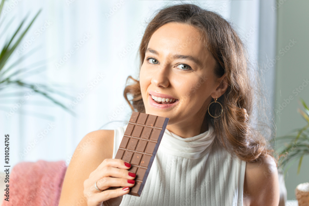 Young woman enjoying a chocolate bar at home. Young woman enjoying a chocolate bar at home.