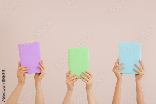 Female hands with books on color background