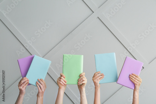 Female hands with books on light background