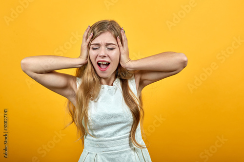 Charming blonde young woman over isolated orange background wearing white shirt keeping hands on head, screaming, announcing. Lifestyle concept