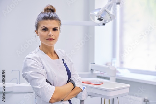 Young confident female dentist doctor with folded arms