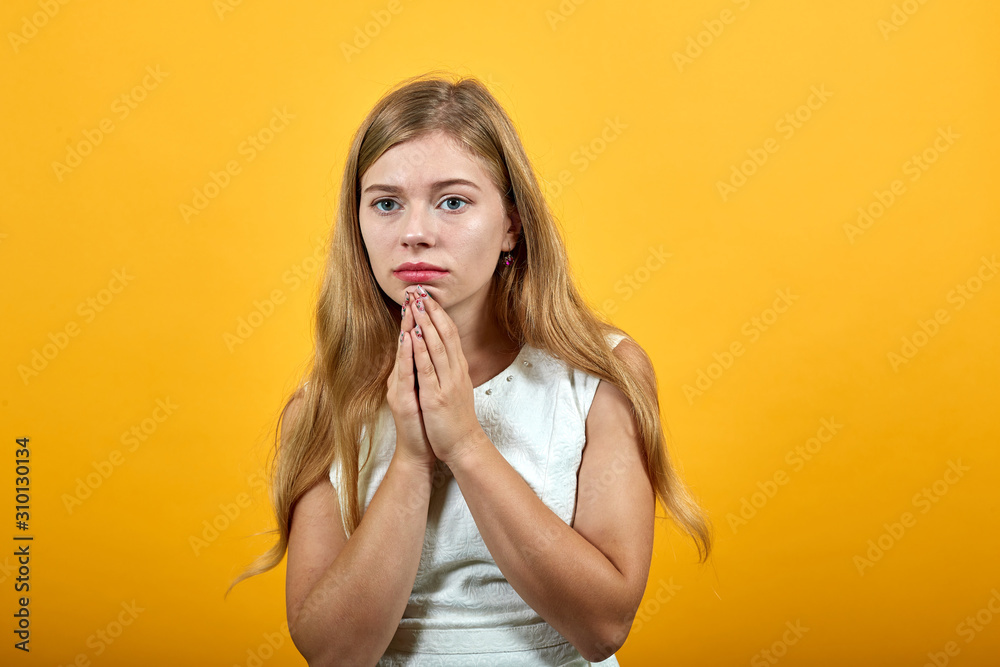 Disappointed caucasian young lady over isolated orange background wearing white shirt keeping hands over chin, looking at camera. Lifestyle concept Disappointed caucasian young lady over isolated orange background wearing white shirt keeping hands over chin, looking at camera. Lifestyle concept
